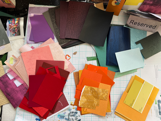Kerrie Bellisario's studio with color-sorted collage papers organized by hue and value.